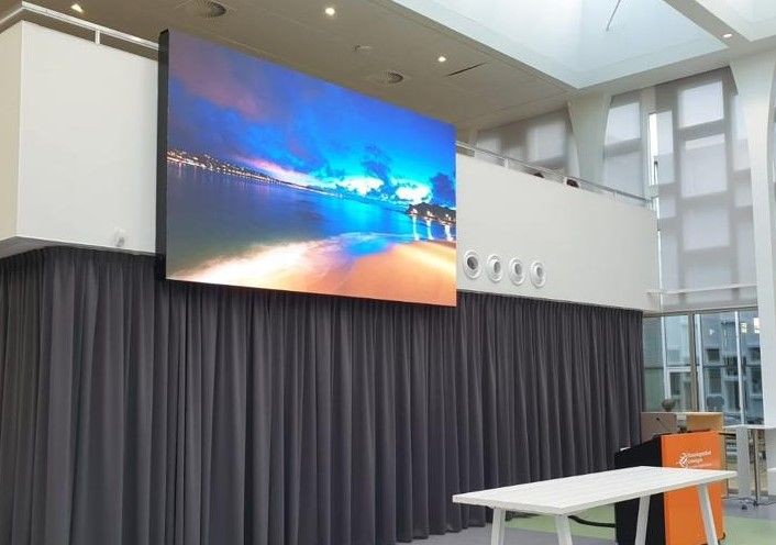 Large display screen in a modern room showing a scenic beach image with vibrant sunset colors.